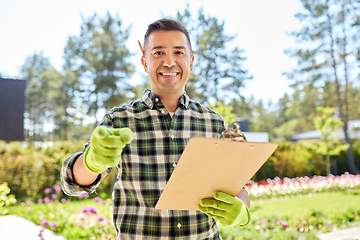 Image showing man with clipboard pointing to camera at garden