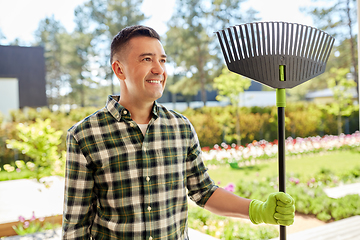 Image showing happy middle-aged man with leaf rake at garden