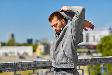 Image showing man stretching hand and shoulder on bridge