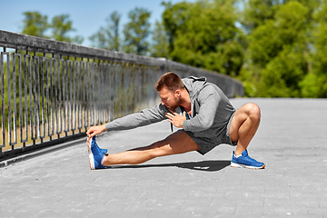 Image showing man stretching leg on bridge