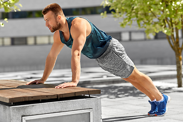 Image showing young man doing push ups on city street