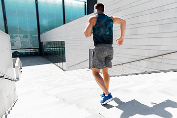 Image showing young man in headphones running downstairs