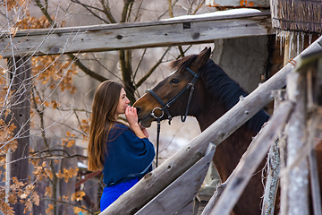 Image showing Portrait of a happy girl hugging a horse, the girl joyfully looks at the horse