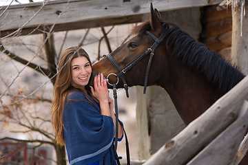 Image showing Portrait of a happy girl hugging a horse, the girl joyfully looks into the frame