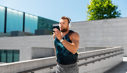 Image showing young man in headphones running outdoors