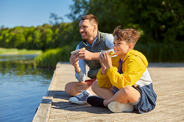 Image showing father and son eating sandwiches on river berth