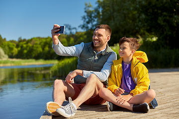 Image showing father and son taking selfie with phone on river