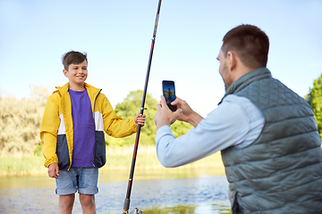 Image showing father photographing son with fishing rod on river