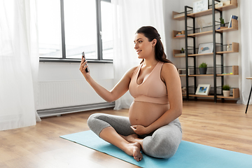 Image showing pregnant woman with smartphone doing yoga at home