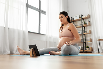 Image showing pregnant woman with tablet pc doing sports at home