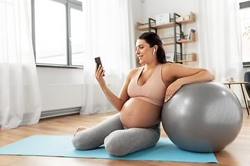 Image showing pregnant woman with smartphone and fitball at home