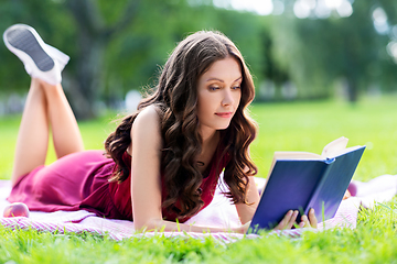 Image showing happy young woman reading book at summer park