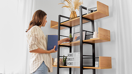 Image showing woman arranging flower and books at home