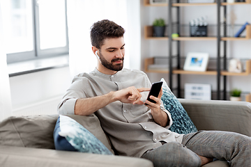 Image showing man in earphones listening to music on smartphone