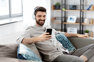 Image showing man in headphones listening to music on smartphone