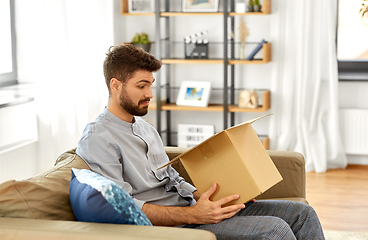 Image showing disappointed man opening parcel box at home