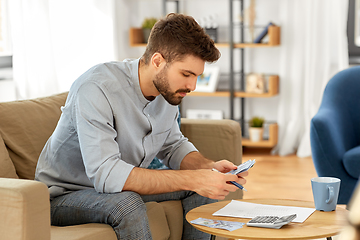 Image showing man with money and calculator filling papers