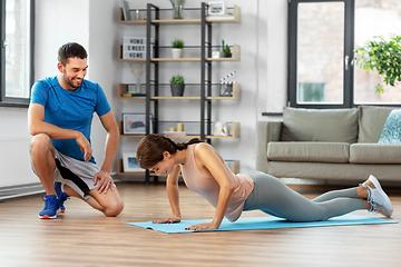 Image showing woman with personal trainer doing push-ups at home