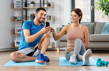 Image showing happy couple with smartphone doing sports at home