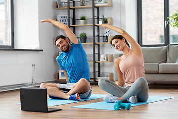 Image showing happy couple with laptop exercising at home