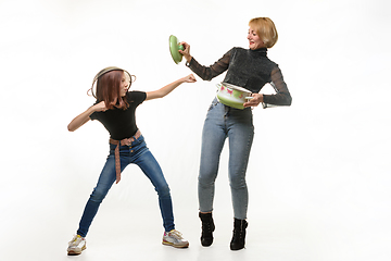 Image showing Mom and daughter have fun using kitchen utensils, the girl attacks, mom defends herself with a pot lid