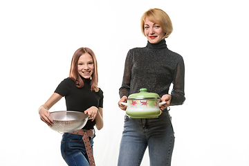 Image showing Mom stands with a saucepan, daughter stands with a sieve, both smile and look into the frame