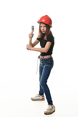 Image showing A girl in a hard hat is preparing to hit with a hammer, isolated on a white background