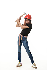 Image showing A girl in a hard hat hit her hard hat with a hammer, a malicious expression on her face