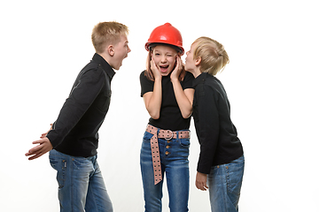 Image showing Two boys are shouting at a girl, the girl is standing in a helmet in a hard hat and plugged her ears, isolated on a white background