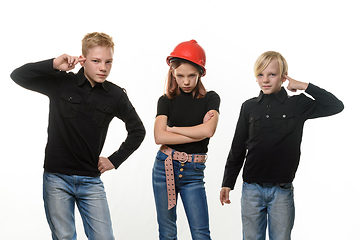 Image showing Two boys tease a girl, the girl is standing in a helmet in a helmet and puffed out her cheeks