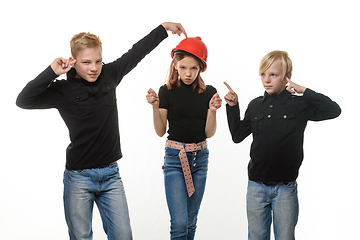 Image showing Two boys are disgusted by the presence of a girl, a girl in a hard hat and shows them a figure