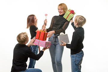 Image showing Children give a gift to mom, boys give a gift in boxes, flower girl