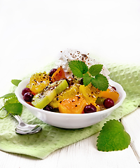 Image showing Salad fruit with cranberries in bowl on light wooden board