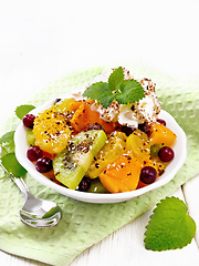 Image showing Salad fruit with cranberries in bowl on wooden board