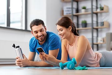 Image showing happy couple with smartphone after sports at home