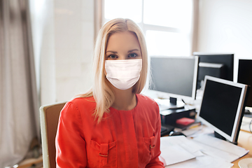 Image showing female office worker in mask with computers