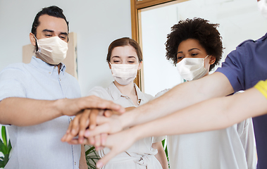 Image showing people in masks stacking hands at office