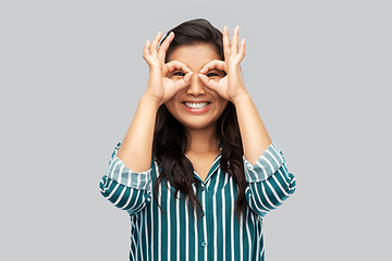 Image showing smiling asian woman looking through finger glasses