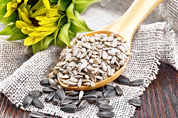 Image showing Seeds sunflower in spoon with flower on board