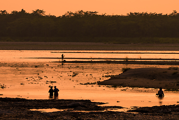 Image showing Asian women fishing in the river, silhouette at sunset