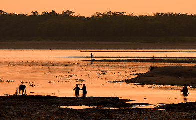 Image showing Asian women fishing in the river, silhouette at sunset