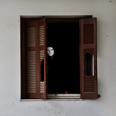 Image showing masked figure and broken window shutter