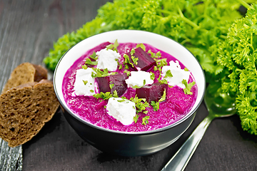 Image showing Soup puree of beetroot with salted cheese in bowl on dark board