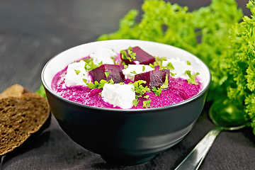 Image showing Soup puree of beetroot with salted cheese in bowl on wooden boar