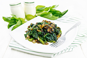 Image showing Spinach fried with onions in plate on light board