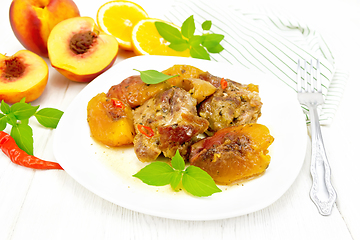 Image showing Turkey with peaches in plate on light wooden board