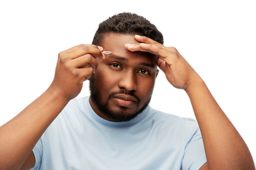 Image showing african man with tweezers tweezing his eyebrow