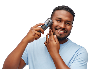 Image showing smiling african man shaving beard with trimmer