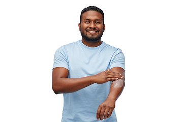 Image showing happy african man applying moisturizer to his hand