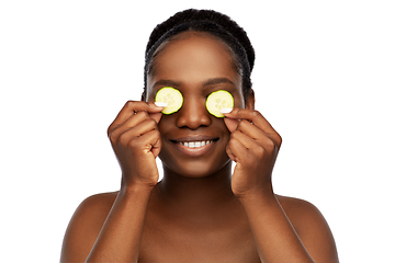 Image showing happy african woman making eye mask of cucumbers